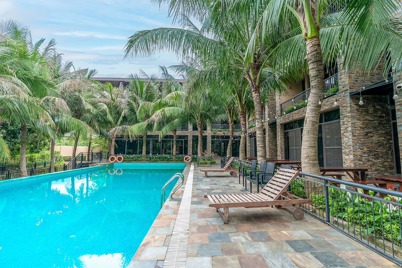 Hồ bơi và khu villa giữa hàng cọ tại Flora Resort